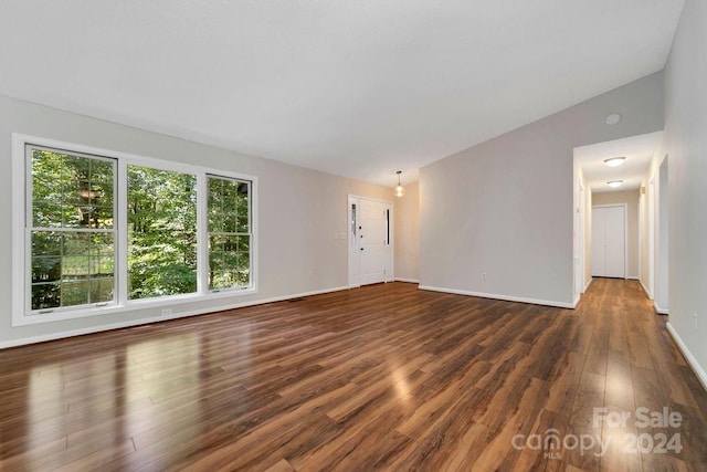 spare room with lofted ceiling and dark wood-type flooring