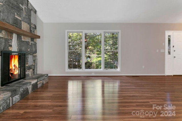 living room featuring a stone fireplace and dark wood-type flooring