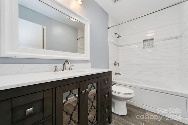 full bathroom featuring tiled shower / bath, vanity, hardwood / wood-style floors, and toilet