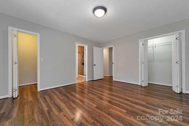 unfurnished bedroom with a textured ceiling, dark hardwood / wood-style floors, ensuite bathroom, and a closet