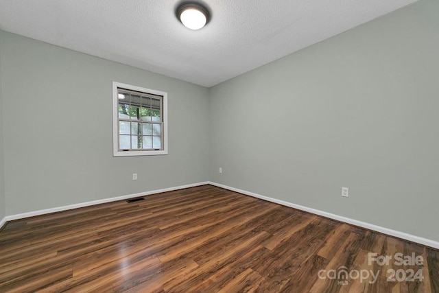 empty room with a textured ceiling and dark wood-type flooring