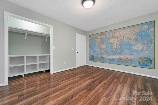 unfurnished bedroom featuring a textured ceiling, a closet, and dark hardwood / wood-style flooring