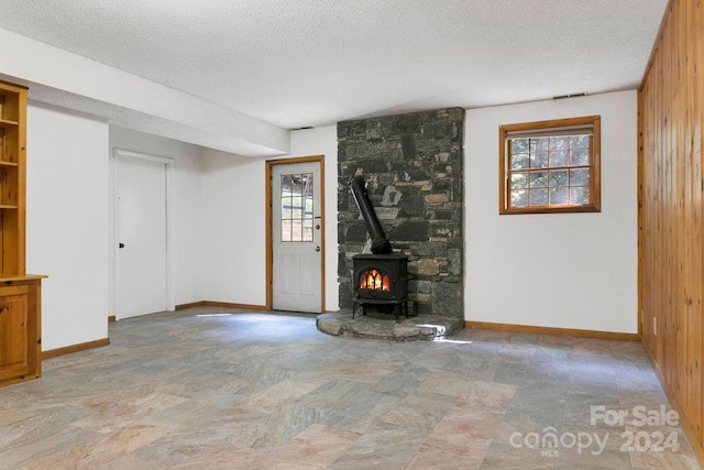 unfurnished living room with a textured ceiling, wood walls, and a wealth of natural light