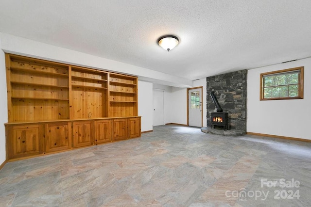 unfurnished living room with a wood stove and a textured ceiling