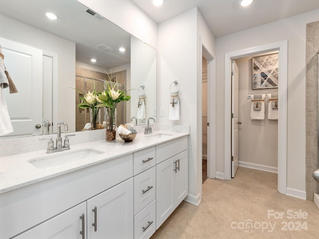 bathroom with a tile shower, vanity, and tile patterned flooring