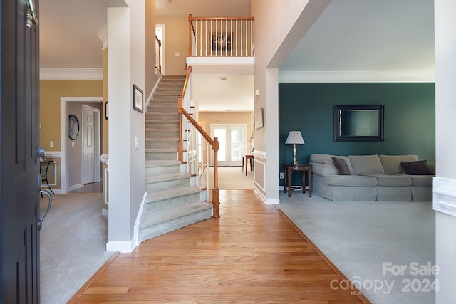 foyer entrance featuring crown molding and light wood-type flooring