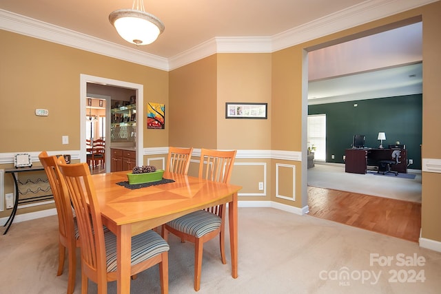 carpeted dining space with ornamental molding