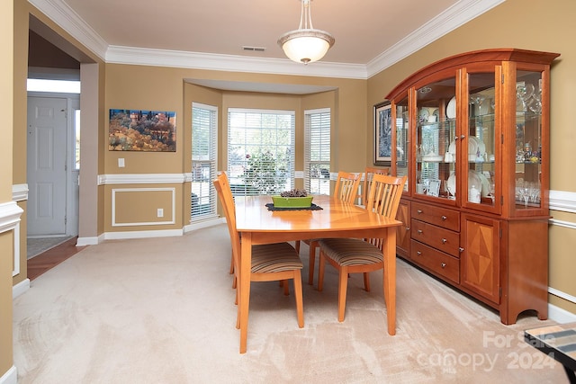 carpeted dining room with ornamental molding