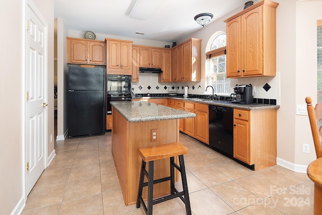 kitchen with tasteful backsplash, black appliances, light tile patterned floors, and a kitchen island