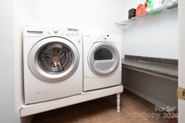 washroom with washer and clothes dryer and dark tile patterned flooring