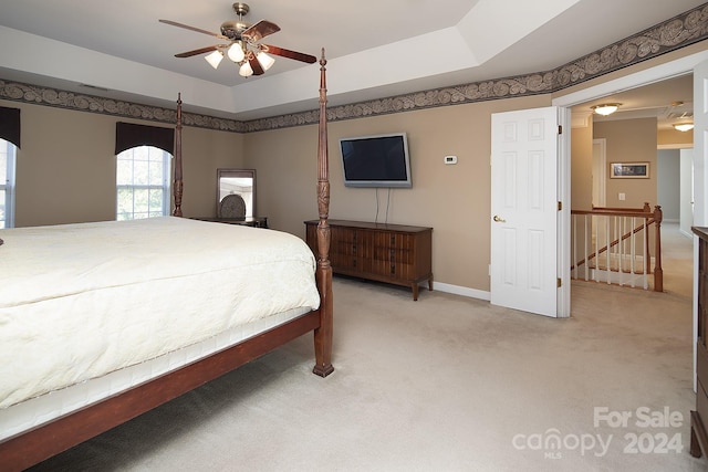 carpeted bedroom with a tray ceiling and ceiling fan