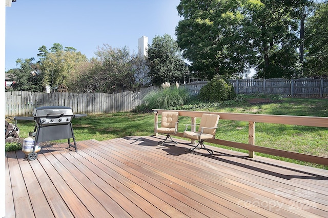 wooden terrace featuring a lawn and a grill