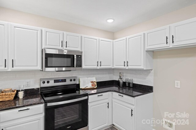 kitchen with white cabinets, stainless steel appliances, backsplash, and dark stone counters