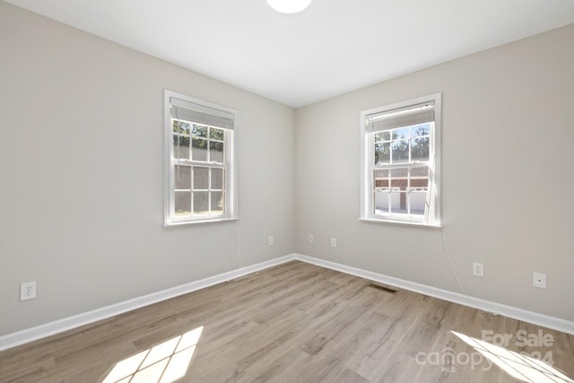 spare room featuring light hardwood / wood-style floors and plenty of natural light