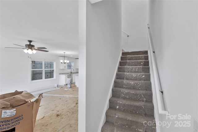 stairway featuring sink and ceiling fan with notable chandelier