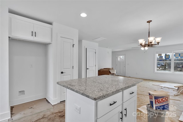 kitchen with white cabinetry, an inviting chandelier, light stone counters, hanging light fixtures, and a kitchen island