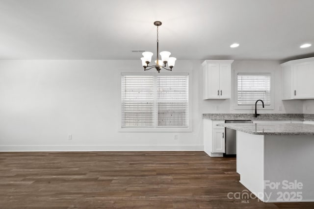 kitchen featuring white cabinetry, light stone counters, decorative light fixtures, dark hardwood / wood-style flooring, and dishwasher