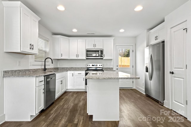 kitchen with light stone countertops, white cabinetry, appliances with stainless steel finishes, and a center island