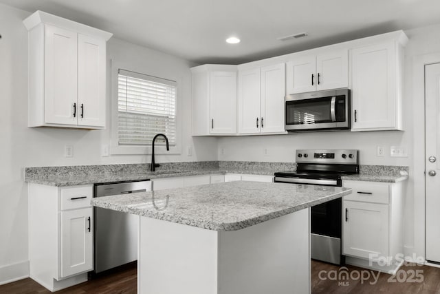 kitchen featuring stainless steel appliances, a center island, and white cabinets