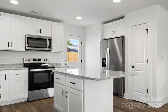 kitchen featuring white cabinetry, a center island, appliances with stainless steel finishes, dark hardwood / wood-style floors, and light stone countertops