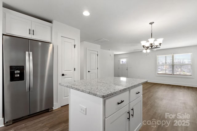 kitchen with decorative light fixtures, stainless steel fridge, white cabinets, and a kitchen island