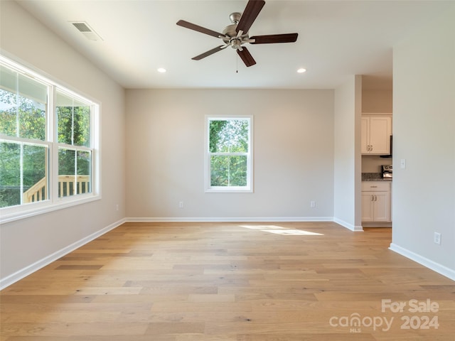 unfurnished room with light wood-type flooring, ceiling fan, and a wealth of natural light