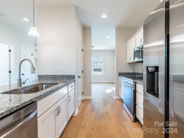 kitchen featuring light hardwood / wood-style floors, dark stone countertops, white cabinetry, stainless steel appliances, and sink