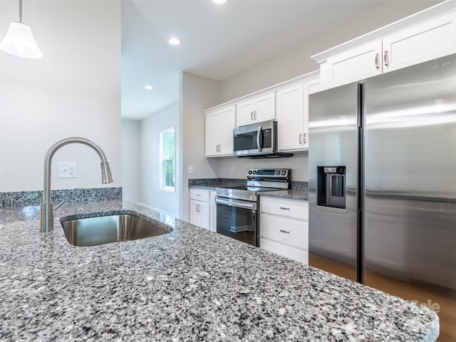 kitchen with decorative light fixtures, sink, stainless steel appliances, and white cabinets