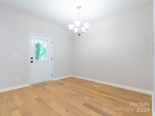 unfurnished room with hardwood / wood-style flooring and a chandelier