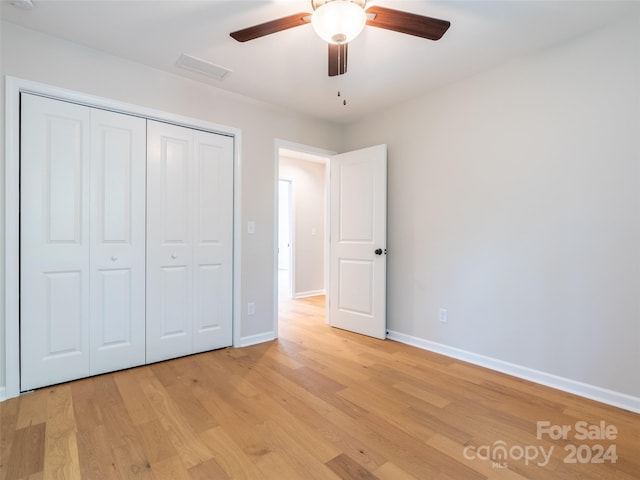 unfurnished bedroom featuring light wood-type flooring, ceiling fan, and a closet