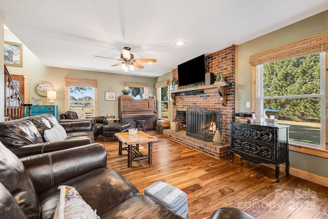 living room with ceiling fan, hardwood / wood-style flooring, a fireplace, and a healthy amount of sunlight