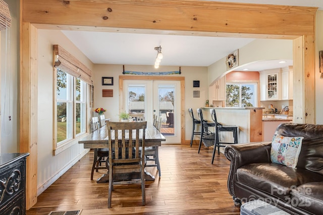 dining room featuring wood-type flooring, french doors, and beamed ceiling