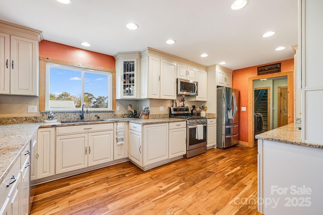 kitchen featuring white cabinetry, appliances with stainless steel finishes, light stone counters, and light wood-type flooring