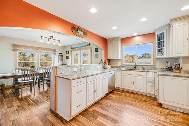 kitchen featuring white cabinetry, dishwasher, kitchen peninsula, light stone countertops, and light hardwood / wood-style floors