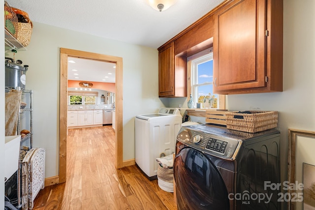 washroom featuring cabinets, washing machine and dryer, and light hardwood / wood-style floors