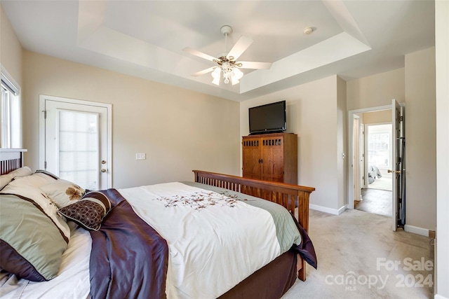 carpeted bedroom with ceiling fan and a raised ceiling