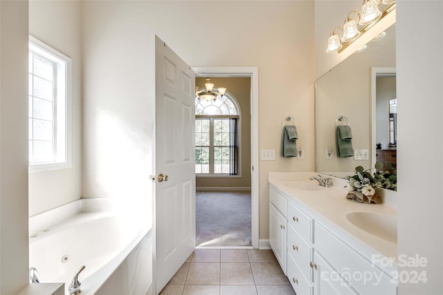 bathroom with a wealth of natural light, vanity, a washtub, and tile patterned flooring