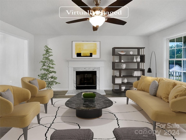 living room with light wood-type flooring, ceiling fan, and a fireplace