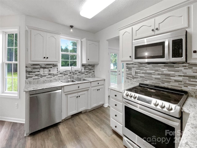 kitchen featuring appliances with stainless steel finishes, light hardwood / wood-style floors, sink, and white cabinets