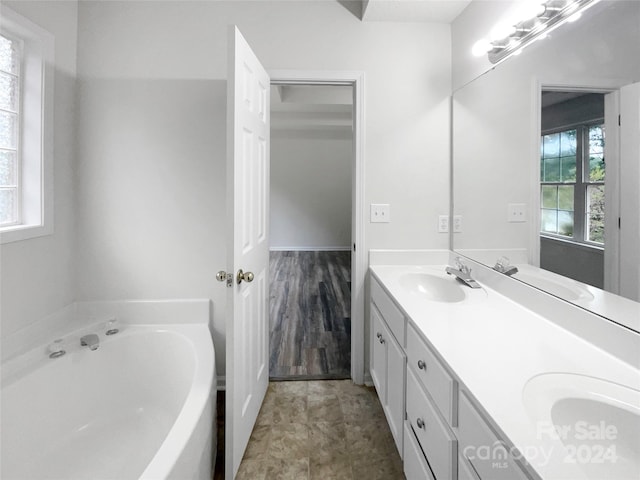 bathroom with wood-type flooring, a tub to relax in, and vanity