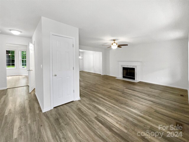 unfurnished living room featuring dark wood-type flooring, ceiling fan, and a premium fireplace