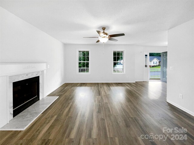 unfurnished living room featuring a textured ceiling, a fireplace, dark wood-type flooring, and ceiling fan