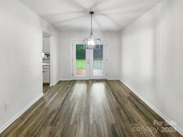 interior space featuring a chandelier, a textured ceiling, dark hardwood / wood-style floors, and french doors