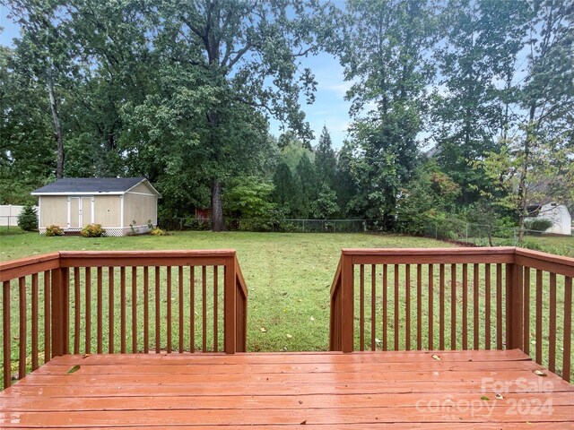 wooden terrace featuring a yard and a storage unit