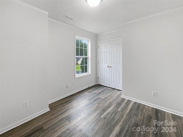 spare room with a textured ceiling, crown molding, and dark hardwood / wood-style floors