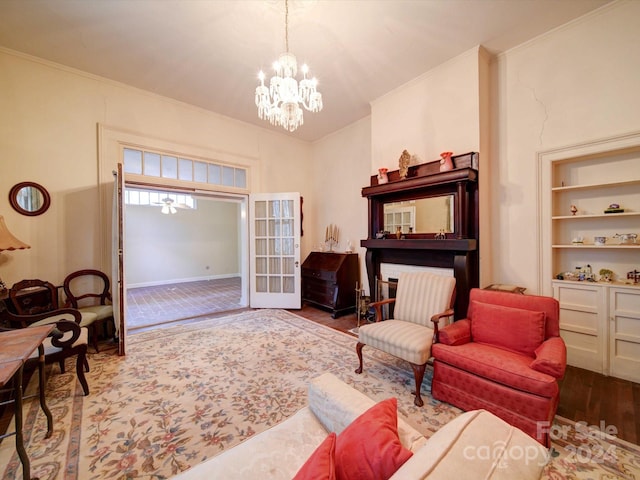 living room featuring wood-type flooring, ornamental molding, a chandelier, and built in shelves