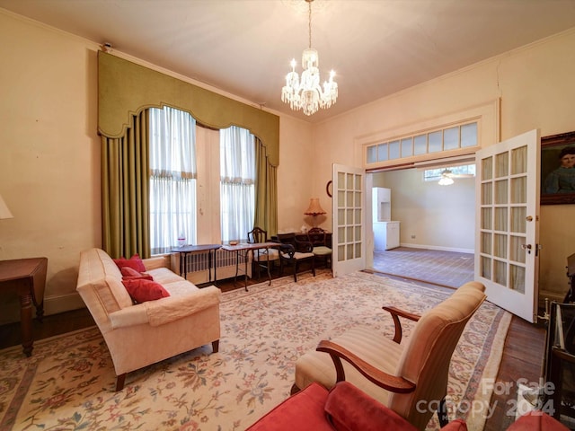 sitting room with french doors, wood-type flooring, ceiling fan with notable chandelier, and crown molding