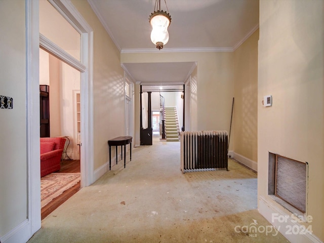 corridor with light hardwood / wood-style flooring, ornamental molding, and radiator heating unit