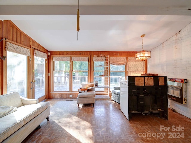 living room featuring wood walls, parquet flooring, vaulted ceiling, heating unit, and an inviting chandelier