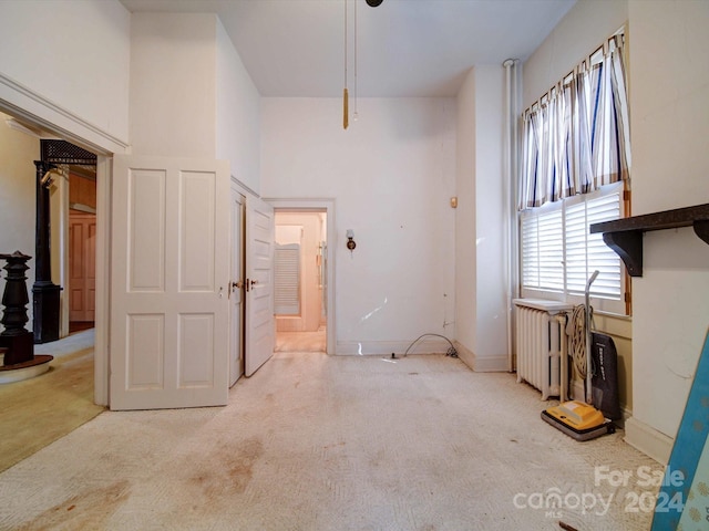 carpeted entrance foyer featuring radiator heating unit and a high ceiling